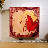 small painting on wood showing a sensual woman with red hair