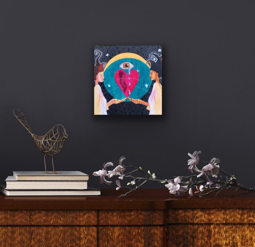 Small mystical painting on a dark grey wall above a dresser with a sakura branch, sculptural bird and books.