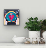 Spiritual artwork by Portland artist Lea K. Tawd hanging on a neutral wall above herbs and plants.