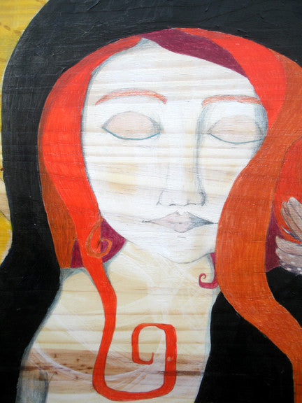 detail of art depicting a woman's face with the wood grain showing as her skin.  She has red hair and a black hood
