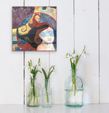 small feminine painting hanging on a shabby chic wall above 3 glass vases with white flowers in them