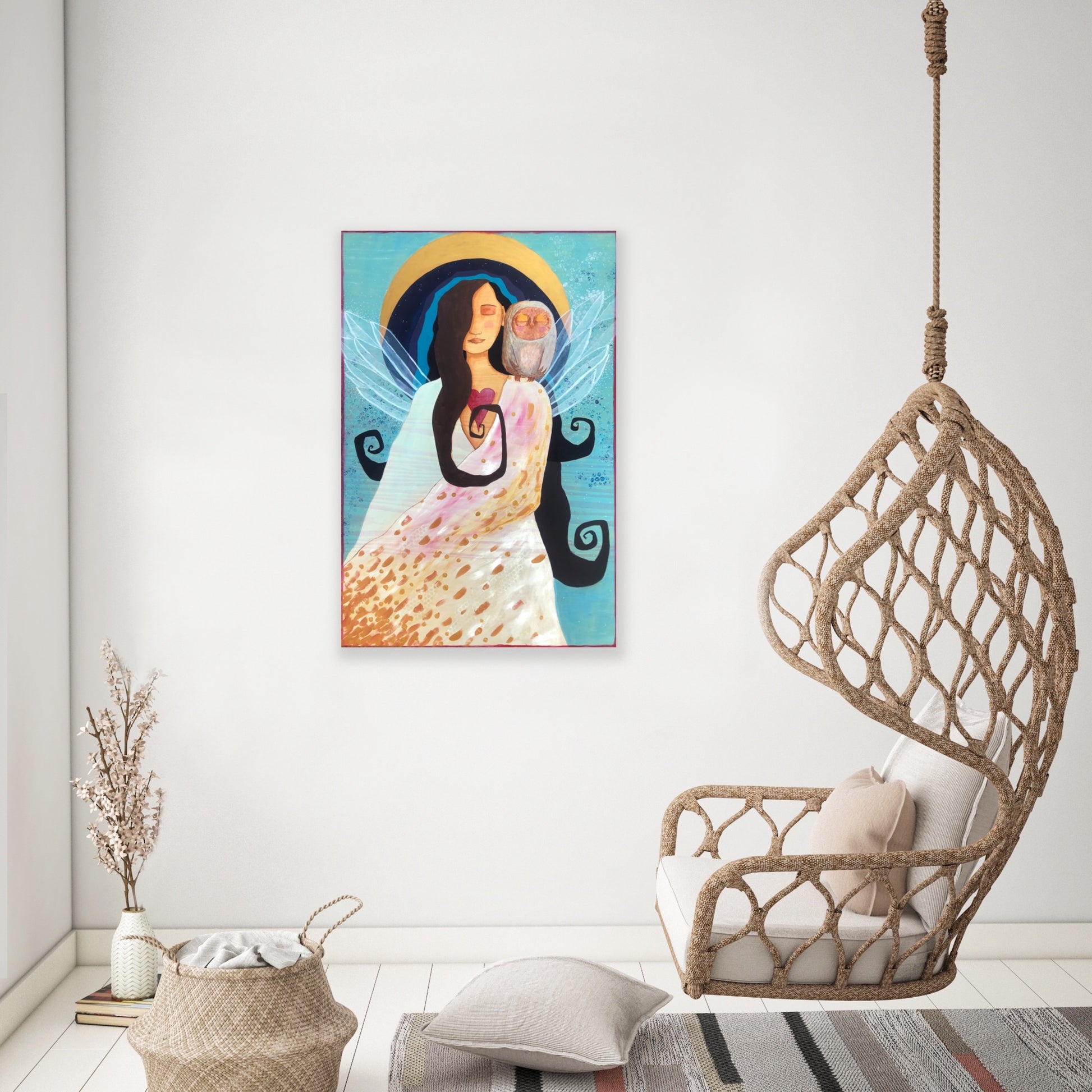 vibrant blue and gold artwork depicting a winged woman with an owl on her shoulder.  the painting is hanging on a white wall in a room with a wicker basket and a wicker chair suspended from the ceiling.