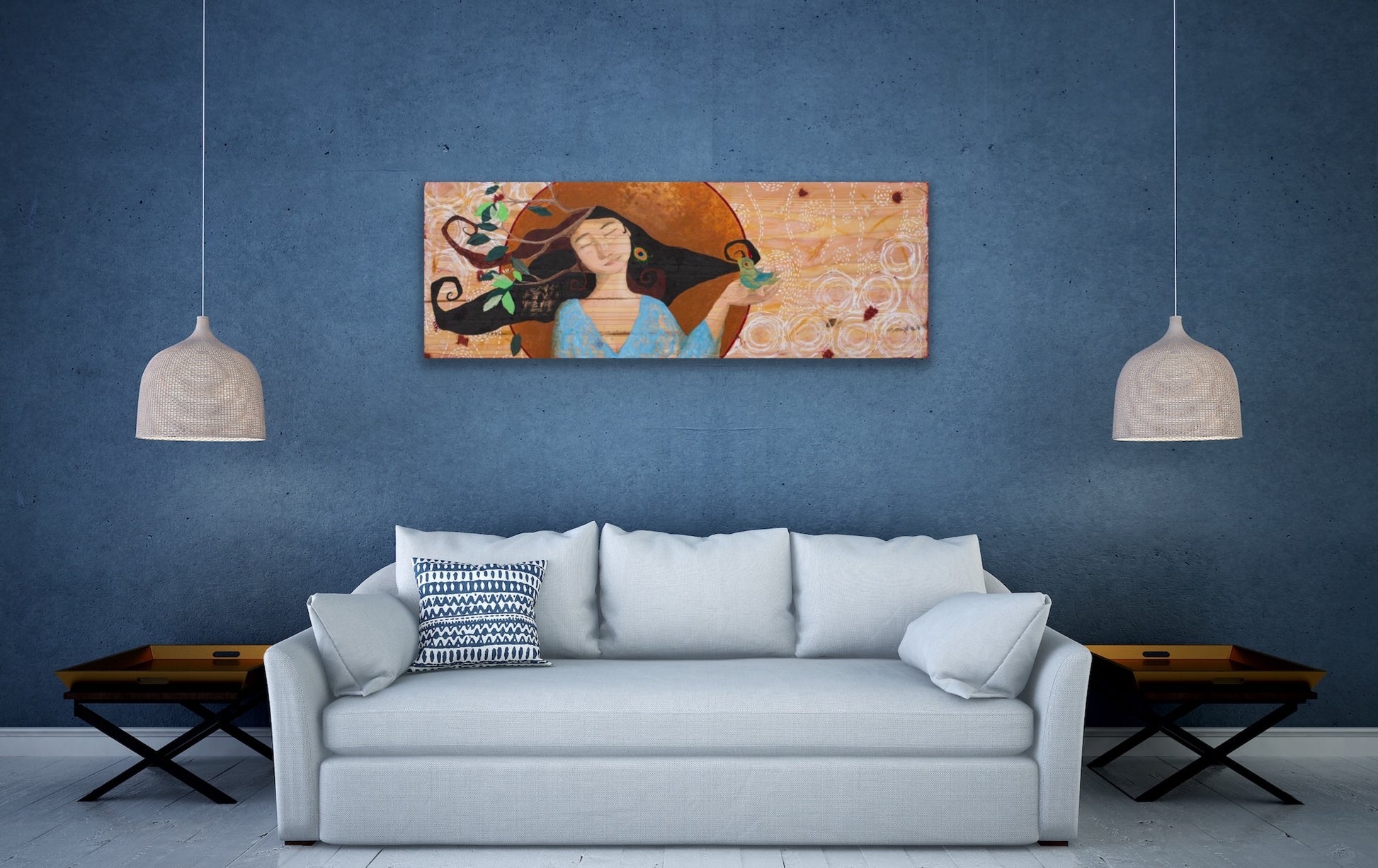 mixed media painting of a woman on wood hanging on a blue wall in a living room with hanging lamps, a white couch, and wooden side tables