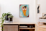 Small painting of feminine angel woman hanging on a white wall above a table with plants on it.